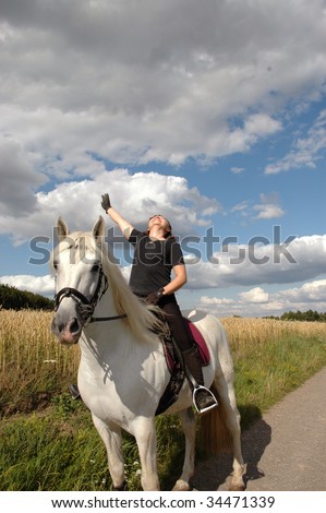 A woman with a raised hand sits on Andalusian horses.