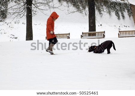A woman walks with the dog in the park.