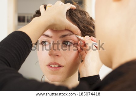 Make up artist hand and her model, real spontaneous image, pulling model eyebrows for better look