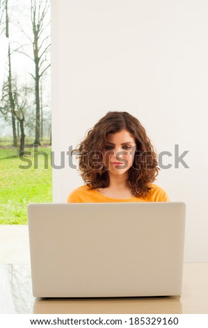 Young woman with laptop at home looking at computer screen