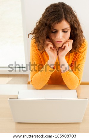 Thinking woman looking at computer screen