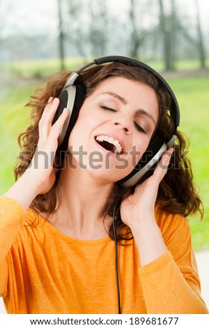 Woman with headphones listening music .Music teenager girl dancing with nature in the background