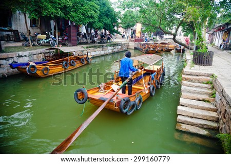 TONGLI, CHINA - JULY 2, 2015: A boat woman transports tourists in her traditional wooden boat in ancient Tongli watertown, Jiangsu province, China on July 2, 2015.
