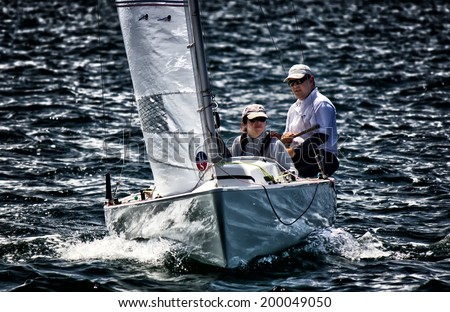 SYDNEY,AUSTRALIA - NOVEMBER 17,2012: A man and woman sail a yacht on Sydney Harbour. Sailing is extremely popular in Sydney, with many clubs for modern and vintage craft.