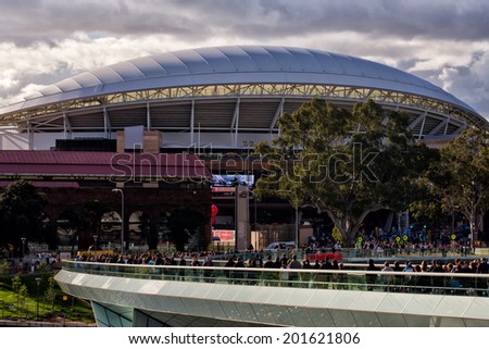 ADELAIDE, AUSTRALIA - JUNE 7, 2014: Fans of Port Adelaide walk to an AFL game at Adelaide Oval. A$535M was recently spent on redevelopment, including A$40M on this footbridge over the river Torrens.