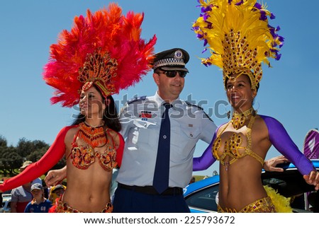 COOGEE,AUSTRALIA - SEPTEMBER 28,2014: A police officer meets Brazilian dancers at a beach soccer tournament between police and international students.