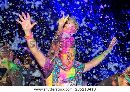 SYDNEY,AUSTRALIA - JUNE 6,2015: Adults and children in the Color Run Night 5K fun run. Runners encounter bubble blowers, coloured powder and UV light, joining a dance party at the finish.