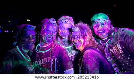 SYDNEY,AUSTRALIA - JUNE 6,2015: Five women in the Color Run Night 5K fun run. Runners encounter bubble blowers, coloured powder and UV light, joining a dance party at the finish.