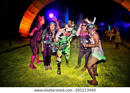 SYDNEY,AUSTRALIA - JUNE 6,2015: Adults wearing costumes in the Color Run Night 5K fun run. Runners encounter bubble blowers, coloured powder and UV light, joining a dance party at the finish.