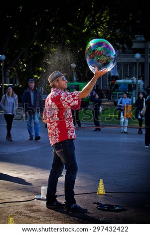 SYDNEY,AUSTRALIA - JULY 4,2015: A street performer spins a soap bubble in the palm of his hand during a performance in Hyde Park.