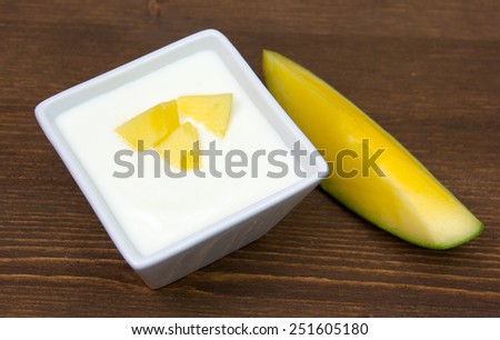 Yogurt with mango on square bowl on wooden table