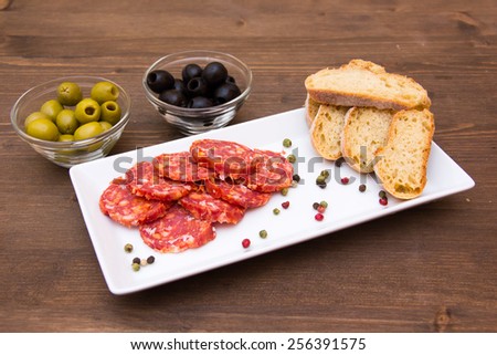 Antipasto of salami and olives on wooden table