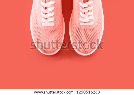 Trend photography on the theme of the actual colors for this season - a shade of orange. Bright orange sneakers on an orange background with a place for an inscription.