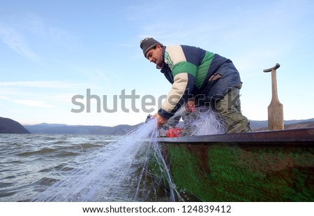 Fisherman throwing net from the boat