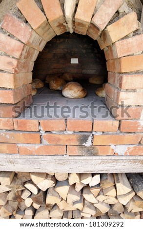 Freshly baked loafs of bread in front of a traditional wood oven outside.