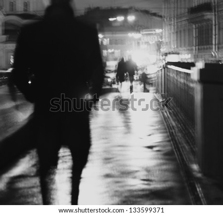 Art photo.Silhouette of a man walking at night on the wet asphalt.