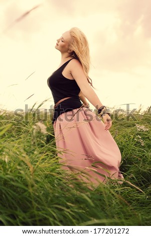 Free woman enjoying nature.Freedom concept.Enjoyment.Toned in warm colors.Vintage style.Wind waving her hair and skirt.