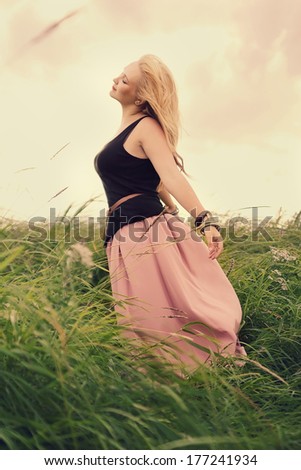 Free woman enjoying nature.Freedom concept.Enjoyment.Toned in pastel colors.Vintage style.Wind waving her hair and skirt.