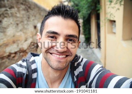 Man taking self portrait in the europe streets.Athens,Greece.Smiling young man.Travel selfie.