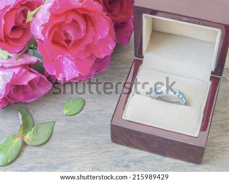 Ring box and pink roses on  wood table for wedding