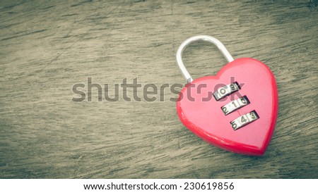Close up red key heart shape on old wooden desk.vintage filter effect