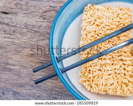 Close up instant noodles in bowl with chopsticks on wood background