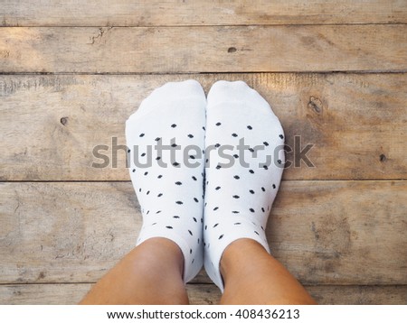 Selfie feet wearing white polka dot socks on wooden floor background