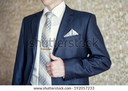 Man in blue suit with tie, tie clip and handkerchief
