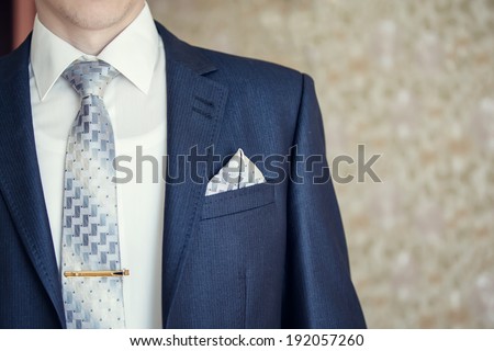 Man in blue suit with tie, tie clip and handkerchief. Focused on handkerchief