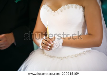 Bride hold a candle. Wedding ceremony in church. Focused on hand.