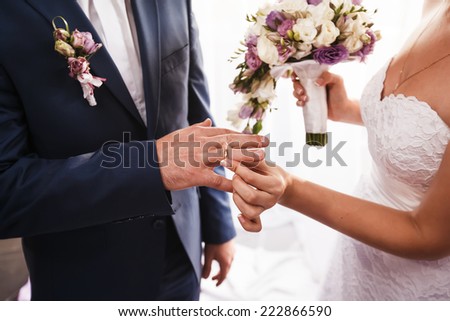 Bride puts on wedding ring on groom\'s finger