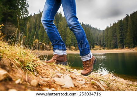 Woman walks up on hill in forest