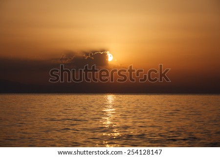 Sunset on sea. Half of the sun is covered by clouds