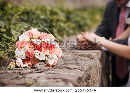 Wedding bouquet close up. Bride\'s and groom\'s hands in background. Shallow depth of field