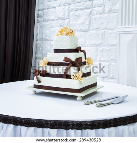 Wedding cake, decorated with brown ribbon and yellow flowers