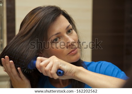 Woman brushing her hair in the bathroom