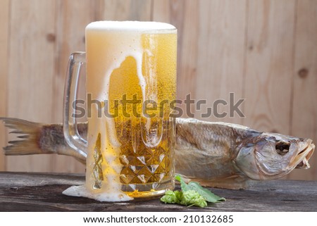 Mug of beer and dried fish on a wood background