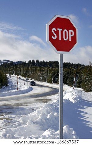Stop sign on mountain road intersection during winter