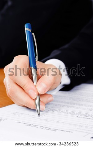 Pen in man\'s hand, filling the tax form