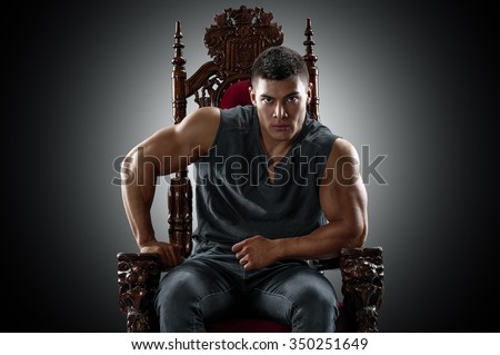 Muscular young man in a T-shirt and jeans, sitting on the throne.