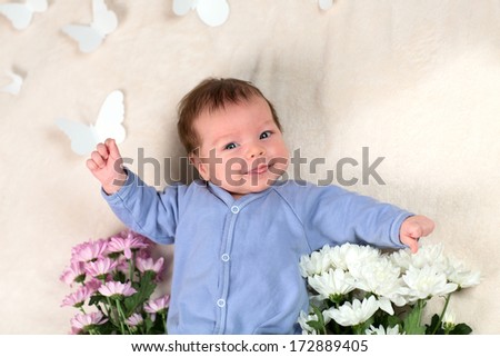 the newborn kid with flowers smiles