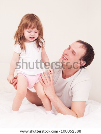 happy family;  father and daughter embracing and laughing in bed at home