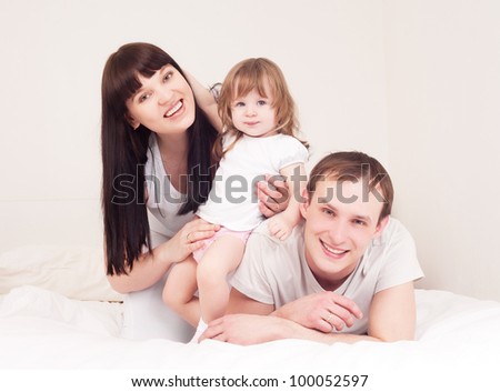happy family; mother ,father and their baby in bed at home