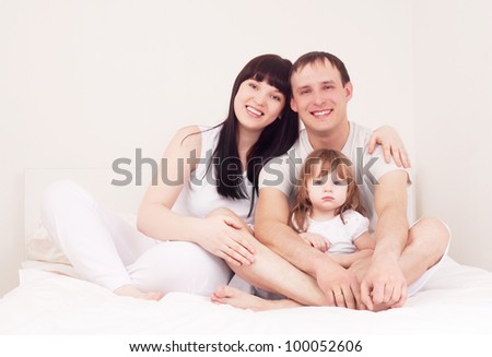 happy family; mother ,father and their baby in bed at home
