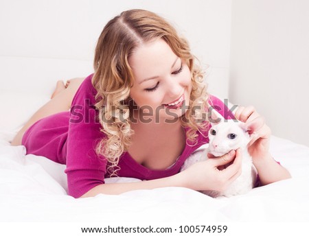 pretty young woman with her cat in bed at home