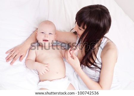 happy young mother and her one year old daughter in bed at home