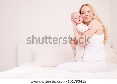 happy young mother and her four months old daughter in bed at home