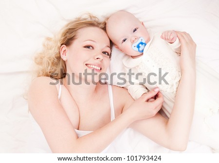 happy young mother and her four months old daughter in bed at home, top view