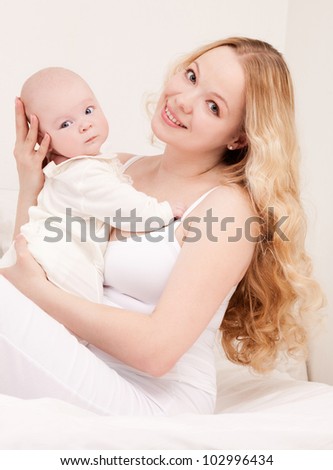 happy young mother and her four months old daughter in bed at home