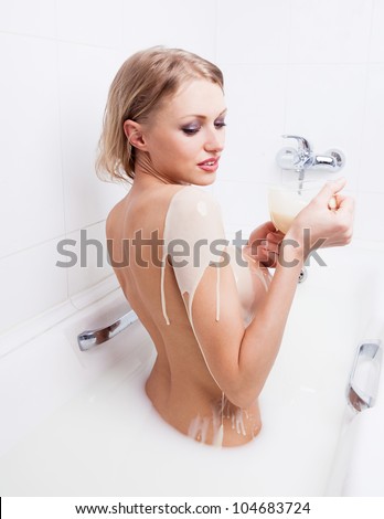 sexy young nude blond woman pouring condensed milk on her body